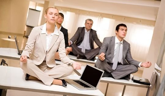 office workers in suit meditating on top of their table